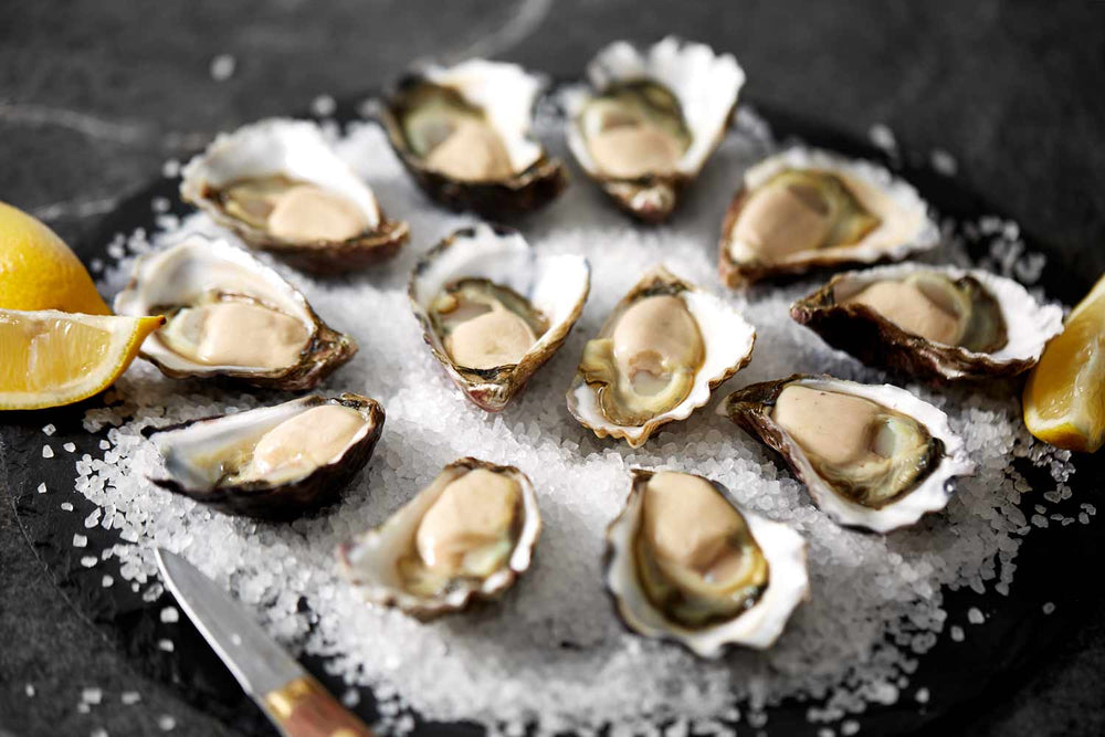 a dozen shucked oysters on serving plate